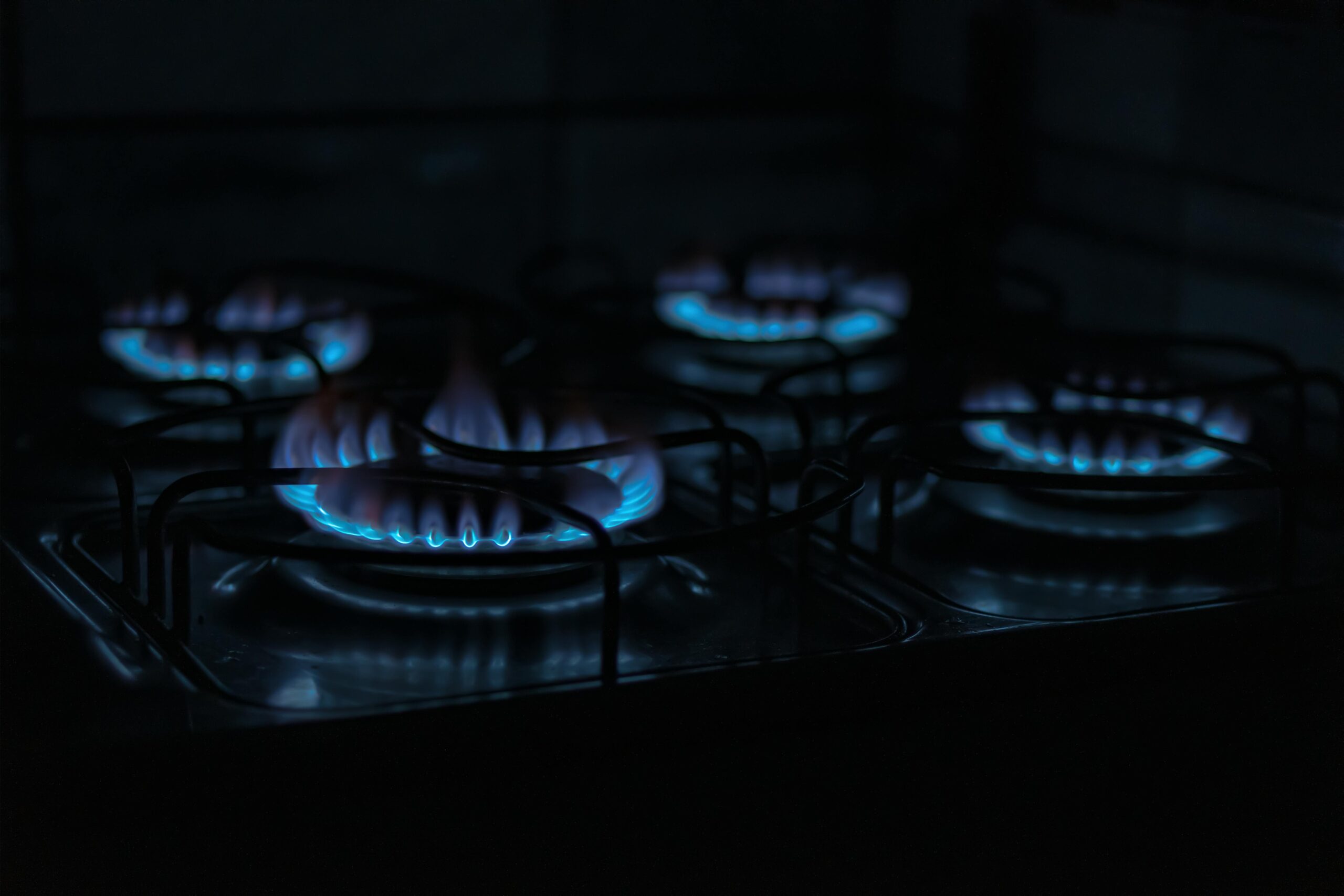 Four lit gas burners on a stove top.
