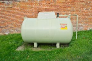 A large propane tank in front of a brick wall